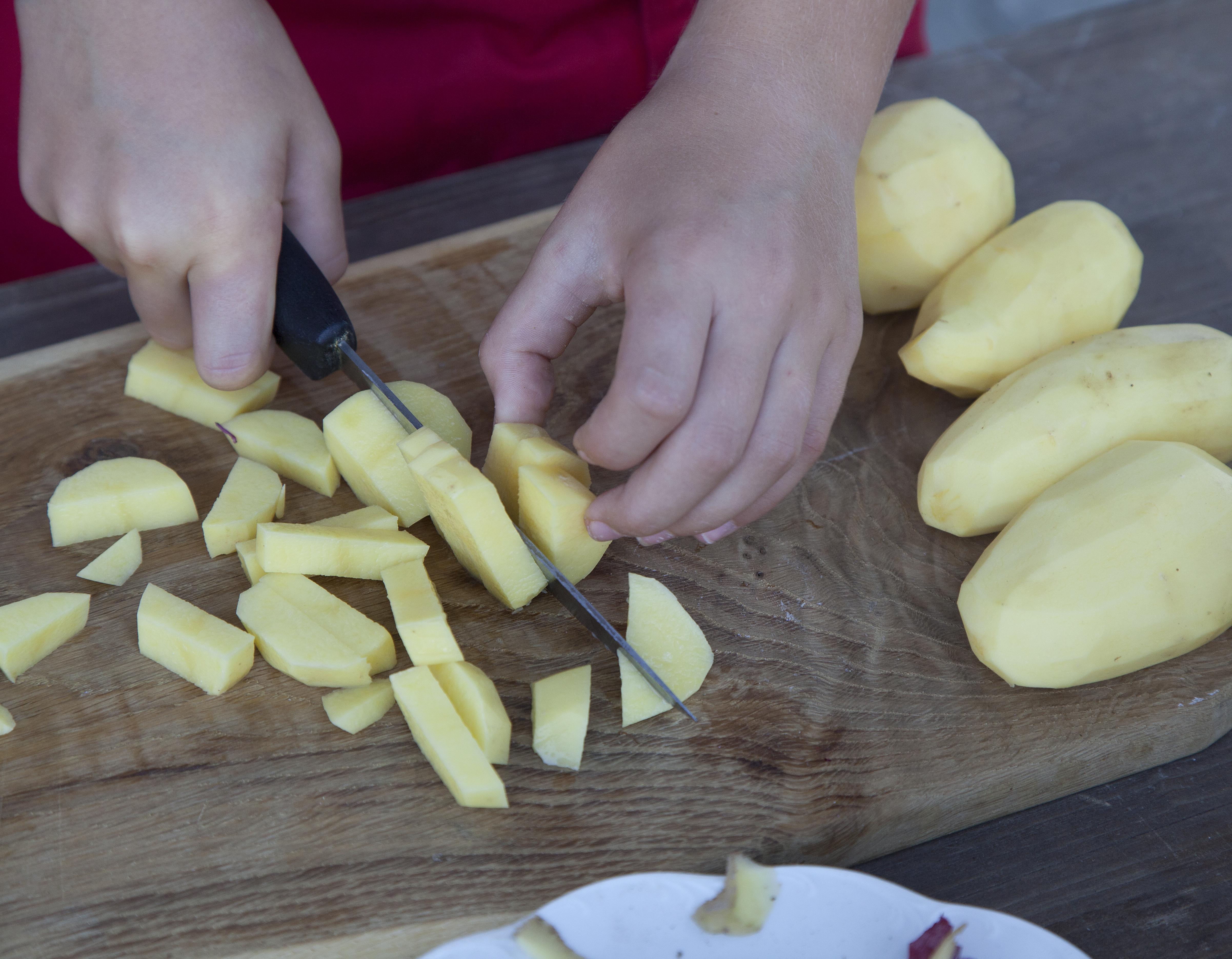 frische-Zutaten-schneiden-für-eine-Kartoffelsuppe-am-Lagerfeuer-kochen-outdoorerlebnis-bei-Straubing