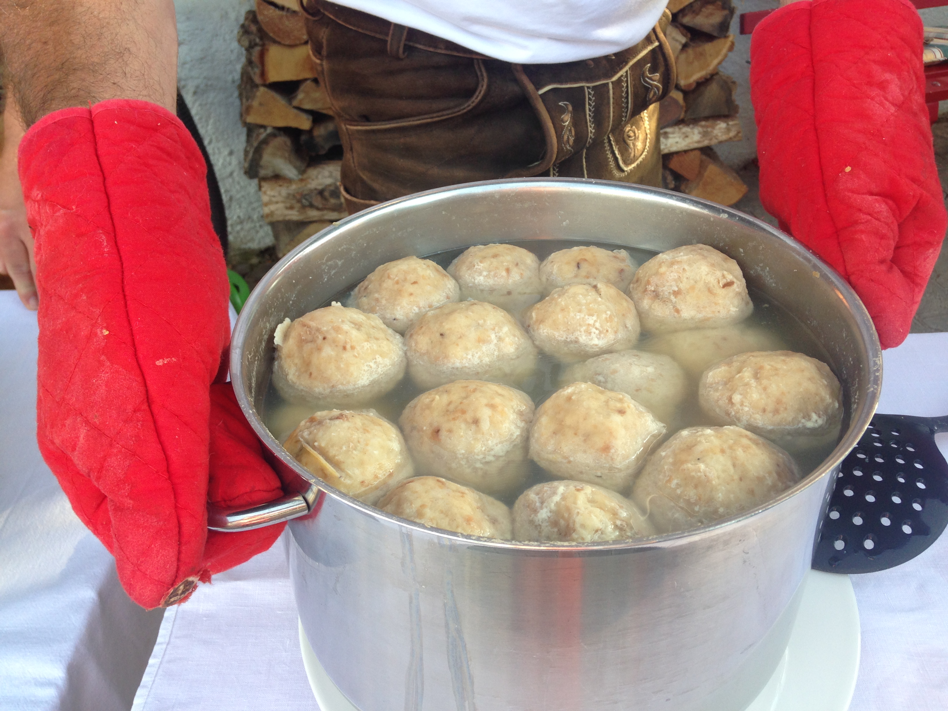 semmelknoedel-schwimmen-in-kochendem-wasser-ein-mann-mit-roten-kochhandschuhen-haelt-den-topf-die-knoedel-dampfen